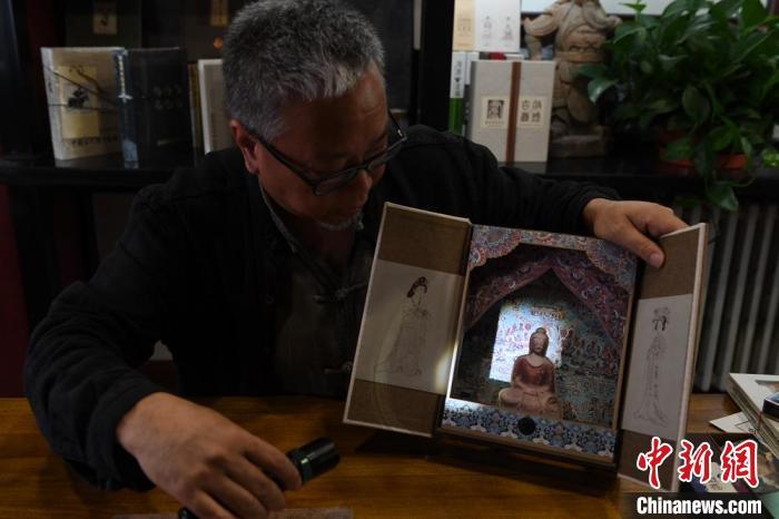 圖為讀者出版集團(tuán)讀者晉林工作室獨(dú)立出品人徐晉林，展示互動性強(qiáng)的敦煌題材手工書。(資料圖) 楊艷敏 攝