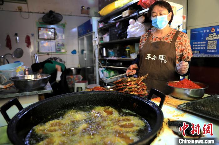 圖為平安驛·河湟民俗文化體驗地內(nèi)的商戶炸干板魚?！⊙Φ?攝